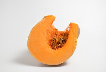A piece of orange pumpkin with seeds on a white background