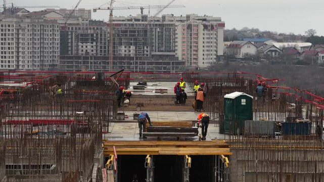 Vertical drone lift above construction site with workers installing rebar and formwork