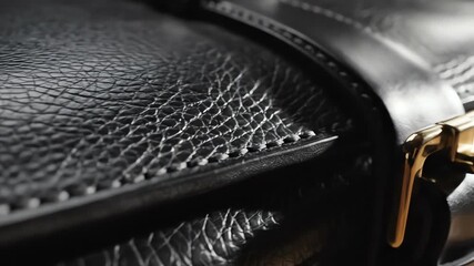 Extreme slow motion close up revealing the intricate stitching and fine grain texture of a pristine black vegetable tanned leather briefcase close, fine, exclusive