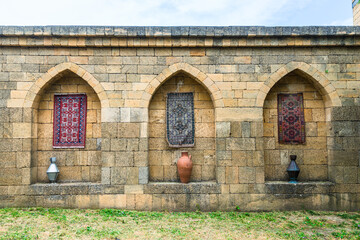The inner side of the old fortress wall of the Naryn Kala citadel decorated with carpets and jugs. Dagestan