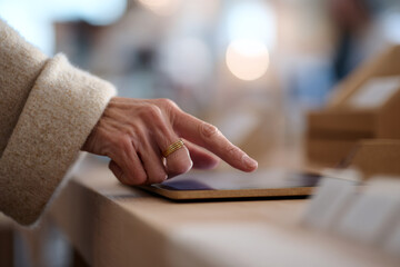 A customer examines a tablet in a store. Close-up of a hand touching the screen while shopping for electronics