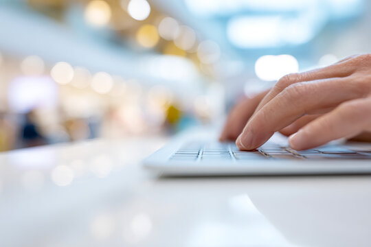 Close-up of a hand typing on a laptop keyboard. Customer testing a computer in a modern store during a sale. Business and technology concept - Powered by Adobe