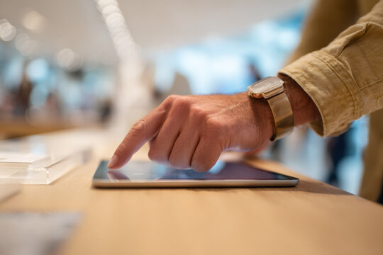 A customer examines a tablet in a store. Close-up of a hand touching the screen of a new electronic device