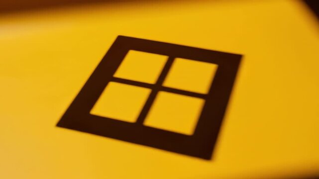 Overhead view tracking alongside the high-contrast shadow of a small square window moving across a brightly saturated sunflower yellow floor Overhead view, square shape, contrast