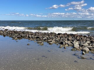 Brandung trifft mit kräftigen Wellen bei Flut auf den Leitdamm in Cuxhaven an der Nordsee