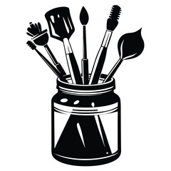 Various black paintbrushes stand creatively inside of a clear glass jar in monochrome style