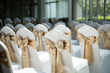 Elegant white wedding chairs with beautiful gold satin bows
