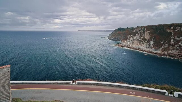 Scenic ocean view at timelapse from a cliffside road in Luarca, Spain with moving sea and clouds.