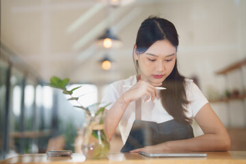 Woman barista thinking using digital tablet in cafe