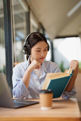 Young woman learning and studying with headphones and book