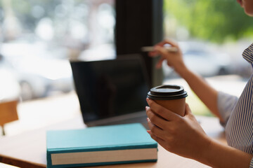 Woman drinking coffee using laptop in cafe