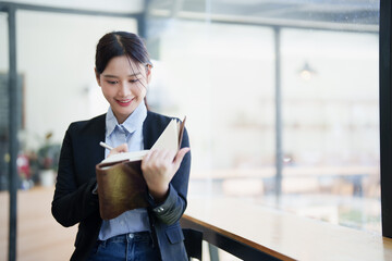 Asian businesswoman smiling writing planning notes in agenda