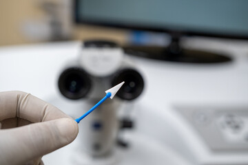 A close-up view of a sterile, disposable fluid-absorbing microsurgical spear (sponge) held by a gloved hand, essential for managing fluids during precise ophthalmic proce