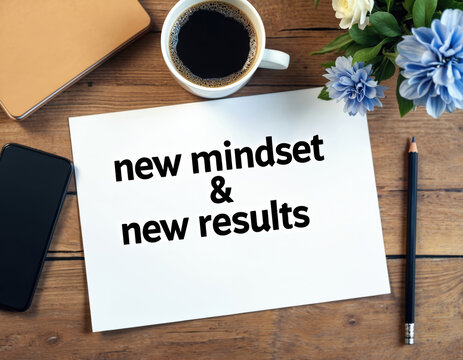 New mindset new results text on white paper at wooden office desk. Flat lay with coffee cup, phone, pencil, flowers. Business concept for motivation, goals, personal development, positive change.