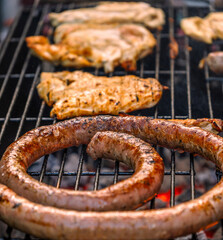 Close-up of delicious Catalan sausages and meat grilling over hot coals on an outdoor barbecue.