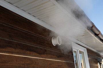 steam billowing from exterior vent near window, moisture-laden exhaust drifting along wooden cladding
