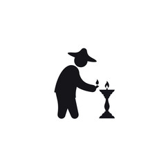 Silhouette of a person lighting a candle on a stand.