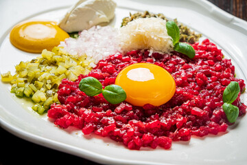 Enjoy a tasty dish of chopped red meat, egg yolk, and fresh herbs on a white plate