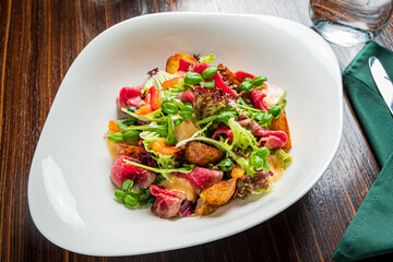 A vibrant salad with tender meat, crisp greens, and fresh veggies served elegantly