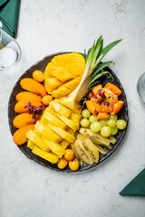 A vibrant mix of fresh pineapple, mango, apricots, and grapes is beautifully arranged