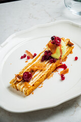 A stunning dessert showcases layered cake topped with colorful fruit and ice cream