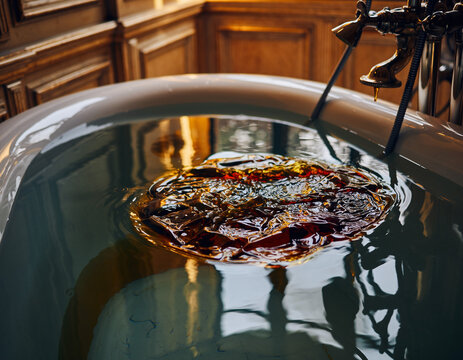 Luxury bath closeup, amber liquid swirls in water. Opulence, relaxation, spa concept. Perfect for wellness, selfcare, and highend lifestyle designs.