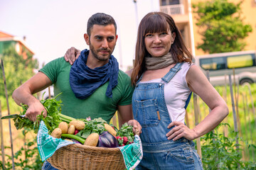 Couple holding a basket filled with freshly picked organic produce from their home garden