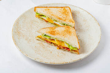 A perfectly toasted sandwich filled with lettuce, cheese, and tomatoes sits on a rustic plate