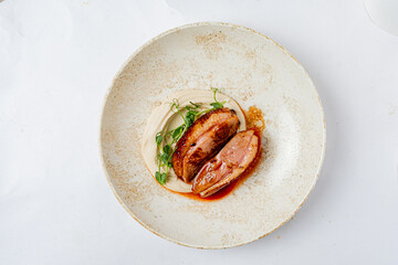 A beautifully plated dish features tender duck breast, creamy sauce, and fresh microgreens
