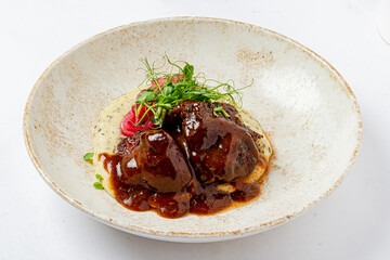 Delicious meatballs resting on smooth polenta, garnished with fresh herbs and a savory sauce