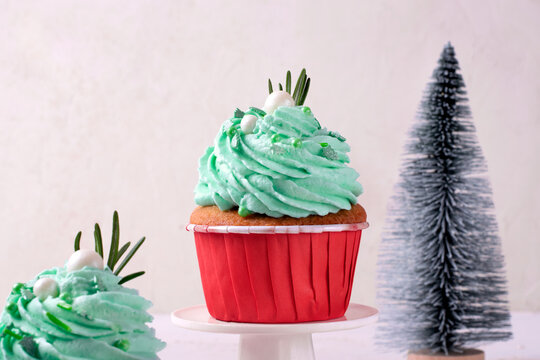 Christmas cupcake with green icing decorated with sugar sprinkles in red cup. Serving size dessert topped with frosting. Celebrating New Year and winter holidays