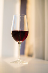 A glass filled with rich red wine catches the warm evening light, perfect for unwinding