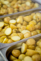 Cooked potatoes glisten in metal trays, ready to be served at a lively lunchtime setting