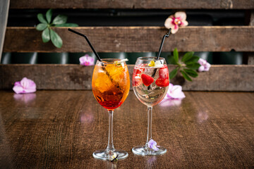 Two vibrant cocktails sit on a rustic table adorned with fresh flowers, capturing a tropical vibe
