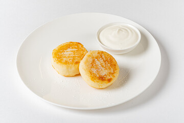 Fluffy pancakes on a white plate, perfectly golden and served with a smooth dipping sauce