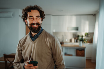 Happy man with beard smiling in modern home kitchen