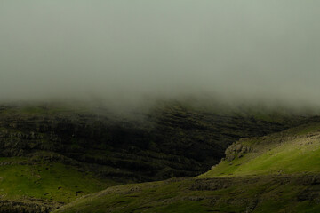 A towering mountain wrapped in dark clouds creates dramatic scenery often encountered by hikers exploring the islands’ rugged trails.