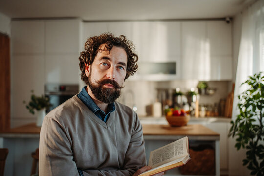 Man reading book in modern home kitchen