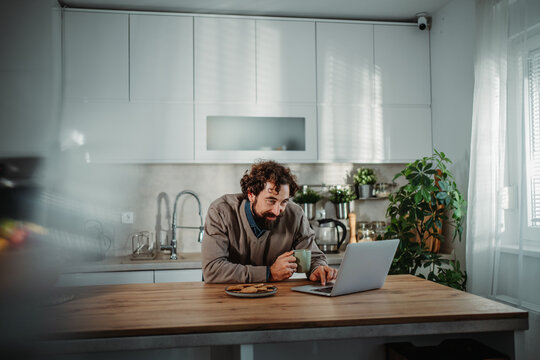 Man working from home on laptop in kitchen