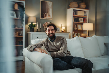 Happy bearded man relaxing on living room couch