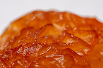 An extreme macro photograph revealing the complex, multi-layered surface of a grape seed, characterized by deep, waxy, translucent folds and convolutions in amber and yellowish-brown