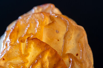 An extreme macro photograph revealing the complex, multi-layered surface of a grape seed, characterized by deep, waxy, translucent folds and convolutions in amber and yellowish-brown