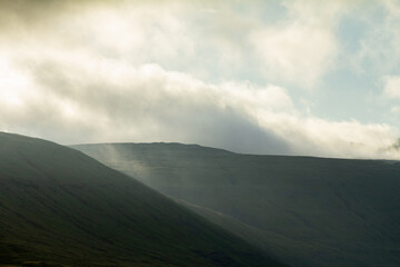 A towering mountain wrapped in dark clouds creates dramatic scenery often encountered by hikers exploring the islands’ rugged trails.