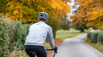 Man riding bicycle down road during autumn season.