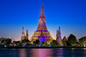 Fototapeta premium 26 November 2025 Beautiful Sunset colours of Thai Temple Wat Arun on Chao Phraya River in BKK Bangkok Thailand. The magic colourful neon light display on the temple at sunset is magical.