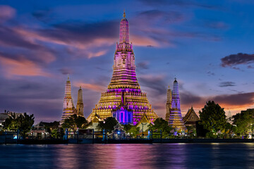 Fototapeta premium 26 November 2025 Beautiful Sunset colours of Thai Temple Wat Arun on Chao Phraya River in BKK Bangkok Thailand. The magic colourful neon light display on the temple at sunset is magical.