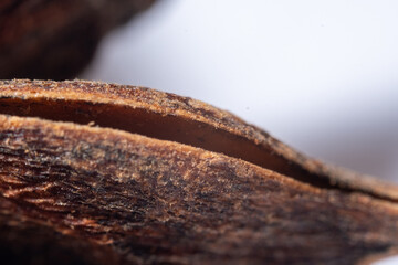 An extreme close-up macro photograph of a dried, deep reddish-brown Star Anise fruit, emphasizing the radially symmetrical structure formed by its woody, boat-shaped fo