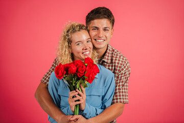 A joyful couple embracing each other while holding a stunning bouquet of red roses, symbolizing their love and happiness together. This image captures the essence of romance and affection beautifully.