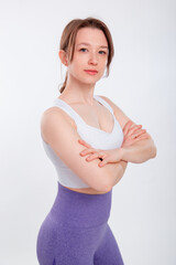 Portrait of a beautiful young fitness woman with her hair up, wearing a sports uniform, posing in a studio against a white background. Healthy lifestyle, sports