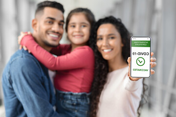 A family, including a happy young girl, poses together while displaying a smartphone with a...